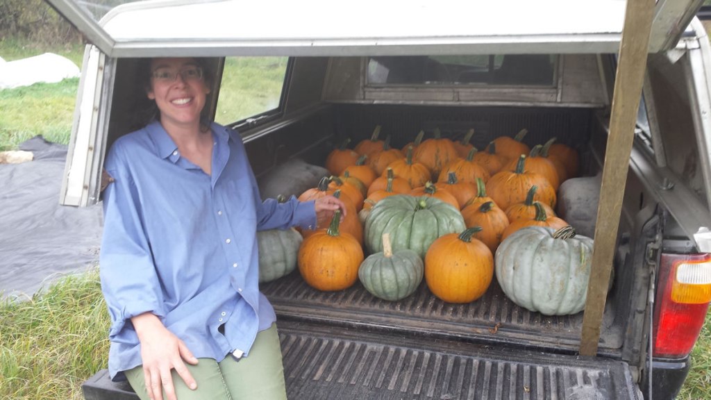A vendor sitting with a truckload of pumpkins